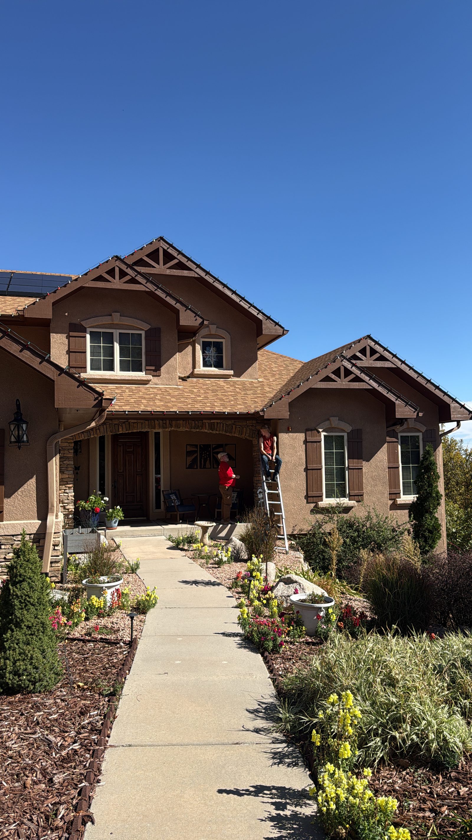 Colorado Springs Christmas light installation in progress on a tan stucco two-story residential home