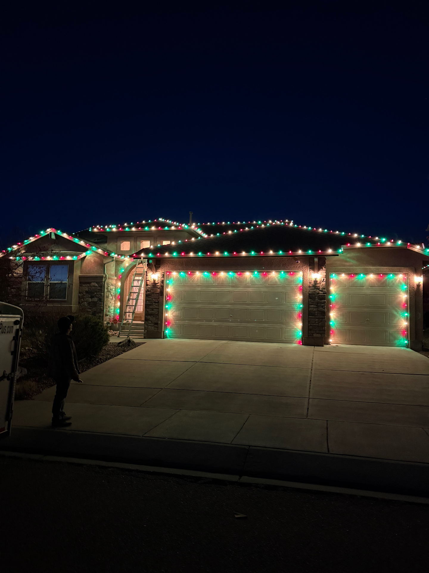 Red and green residential Christmas light installation across a home's roofline and garage in Colorado Springs