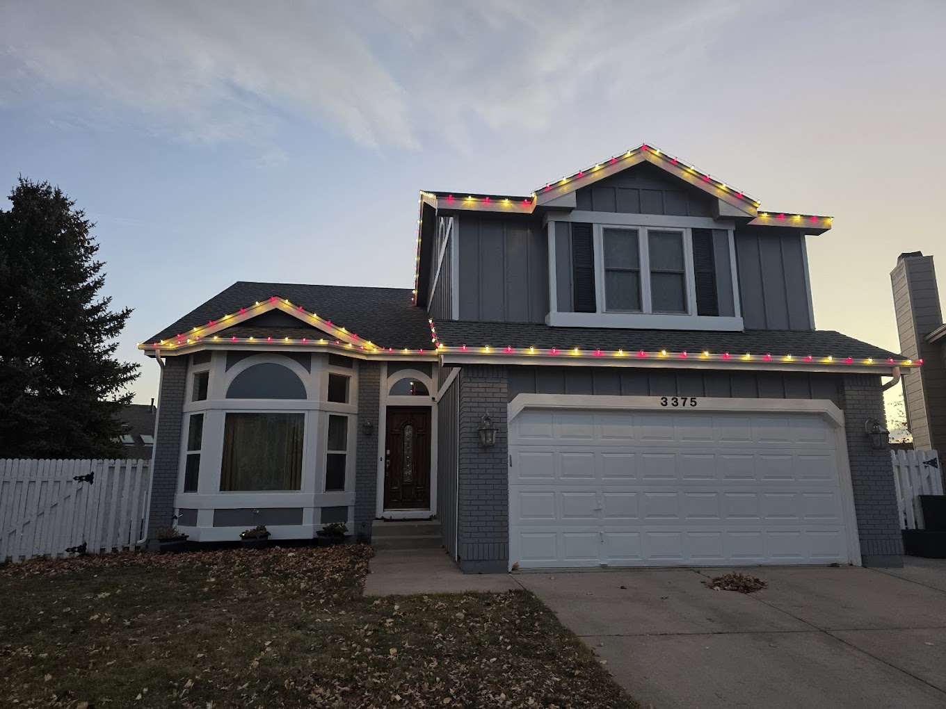Two-story Colorado Springs home decorated with multicolor roofline Christmas lights for the holiday season