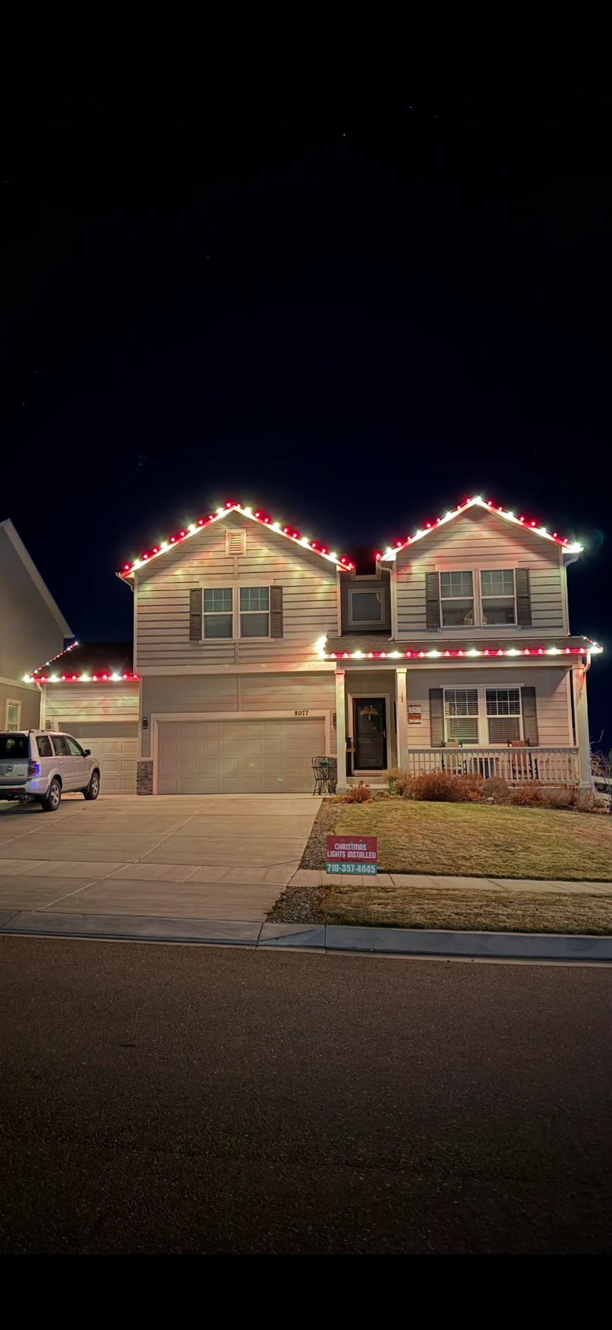 Professional Christmas light design example - red and white LED roofline lights on two-story home, garage lighting, festive holiday display completed by expert installers